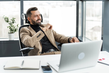 Satisfied businessman sitting on an office chair and resting