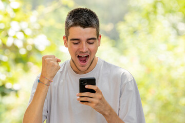 excited young man celebrating looking at mobile phone
