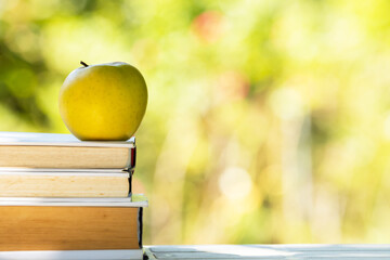 stacked books with apple outdoors