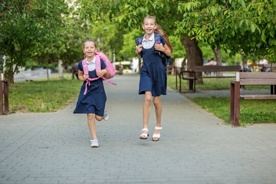 Two schoolgirls run to school with backpacks. Having fun. Concept back to school, learning