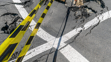 Dangerous stretch of road with damaged asphalt. The accident site is fenced off with black and yellow tape. The concept of repair or accident of sewerage, underground communications, water supply.