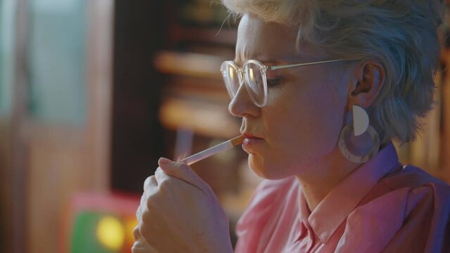 Serious female journalist lighting up cigarette, smoking, working on article