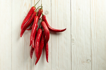 Red hot chili peppers are dried on a thread. On a white wooden background.