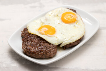 three fried ground meat with fried egg on white plate