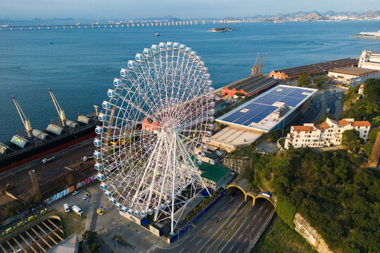 Rio de Janeiro, Brazil - August 3, 2022: Aerial view of Yup Star (Rio Star) ferris wheel and large industrial cargo ship.