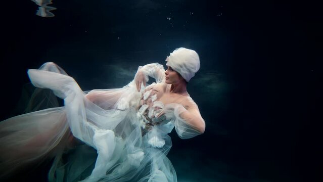 sea fairy is floating underwater, slow motion subaquatic shot with stunning lady in white gown