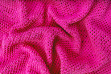 Fototapeta na wymiar Close up background of knitted wool fabric with dots pattern. Bright pink color crumpled knitting wool knitwear texture. Openwork abstract knitted jersey fabric abstract backdrop
