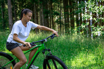 Obraz premium A young woman rides a bicycle in a mountainous area in the forest.