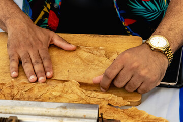 Process of making traditional cigars from tobacco leaves with hands using a mechanical device and...