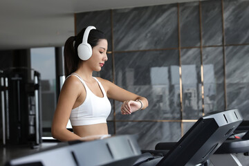 Beautiful attractive woman listening music and exercise on treadmill machine in gym fitness, urban...