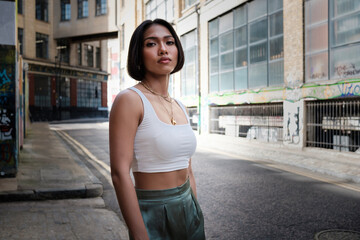 Fototapeta premium Portrait of asian female standing in a narrow London street looking at camera.