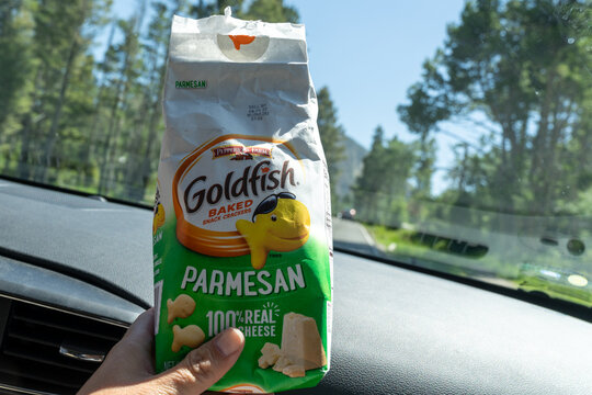 Wyoming, USA - July 18, 2022: Hand holds up a package of parmesan cheese flavored Goldfish baked snack crackers while in a car on a road trip