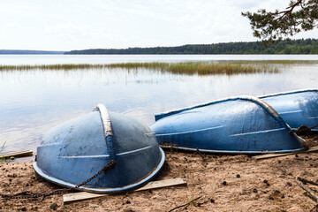 Blue rowboats lay head over heels on a sandy beach
