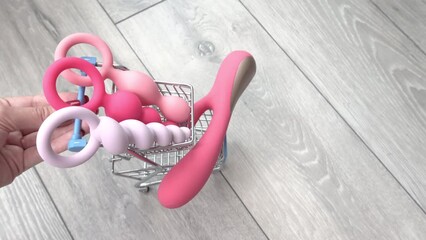riding supermarket trolley filled with sex toys vibrator and butt plugs. Concept of buying adult toys, e shopping 