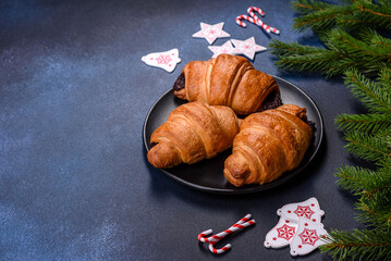 Crispy chocolate croissant with Christmas decorations on wooden cutting board