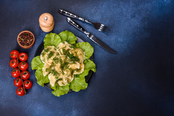 Delicious fresh cooked dumplings with potatoes embellished with greens and lettuce leaves on a dark...