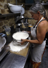 panadera profesional trabajando la harina ecológica artesanalmente con un tamiz