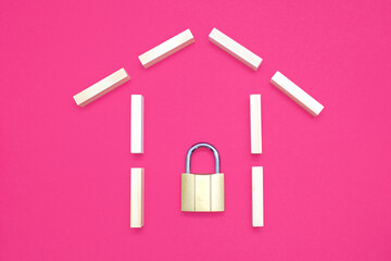 House shape from wooden rectangles on a pink background with a closed padlock. The concept of...