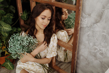 Beautiful girl in a dress sits on a chair