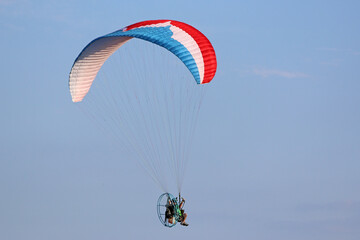 Paramotor pilot flying in a blue sky	