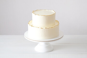 Cake with white cream, decorated with gold confectionery sprinkles on a white background....