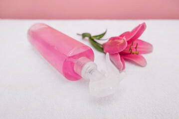 Spray bottle with pink liquid and rose flower.