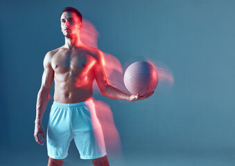 Fit male athlete posing with pink ball in white shorts on blue background. Motion, activity,...