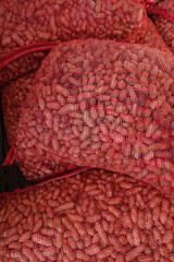 Red Mesh Bags Full of Whole Raw Peanuts Still in their Shells Background