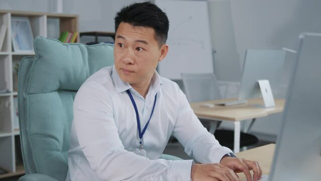 Asian professional male hiding smartphone, texting message in office. Young businessman using mobile apps for business time management.