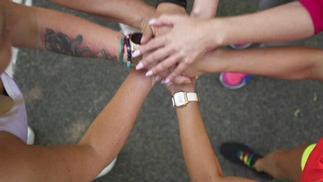Group of women stacking hands together during running workout at park