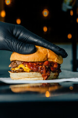 hand stacking a cheese burger with barbecue