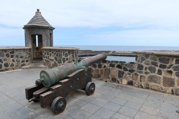 Fototapeta na wymiar Puerto de la Cruz, Tenerife, Canary Islands, Spain, May 27, 2022: Old cannon and sentry box on the boardwalk at the entrance to the port in Puerto de la Cruz, Tenerife