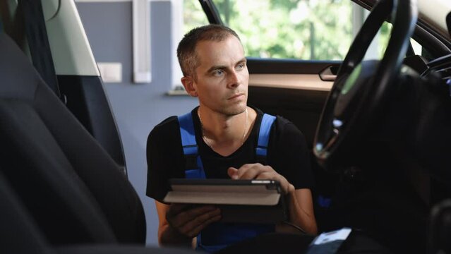 Professional car mechanic repair service and checking car engine by diagnostics software on tablet computer. Expertise mechanic working in automobile repair garage