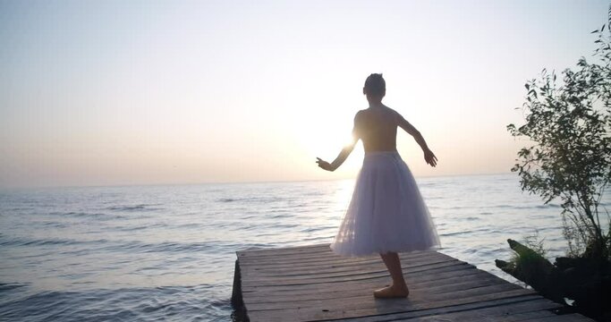 Wide shot confident graceful young woman in tutu and pointies performing in slow motion on the right in sunrays. Caucasian beautiful ballerina dancing in sunshine at sunset. Cinema 4k ProRes HQ