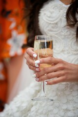 A glass of alcoholic beverage in the hands of an adult.