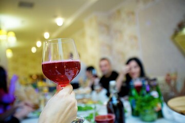 A glass of alcoholic beverage in the hands of an adult.
