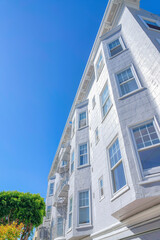 Low angle view of an apartment with white lined stucco walls and bay windows at San Francisco, CA
