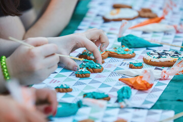 A teenager's hand is decorating a gingerbread. Delicious and creative activity for children and adults.