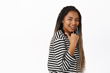 Portrait of smiling african woman pointing left, showing logo or promo offer, demonstrating sign, standing in casual clothes over white background