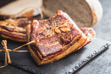 Whole smoked bacon on cutting board.