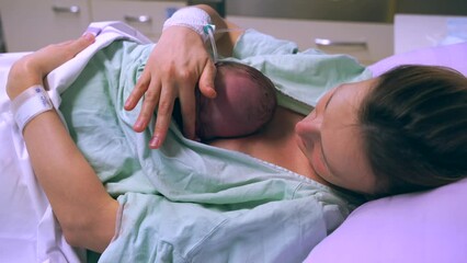 Mother and newborn. Child birth in maternity hospital. Young mom hugging her newborn baby after delivery. Woman giving birth. First moments of baby life after labor.