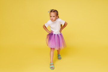 Portrait of offended little toddler girl child over yellow background. Looking at camera. Advertising childrens products.