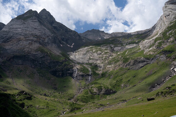 waterfalls on mountains slopes leading down to grass meadows