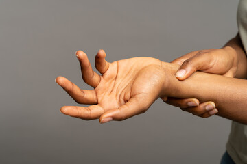Close up of african woman arms holding painful wrist after work on laptop computer, suffering from...