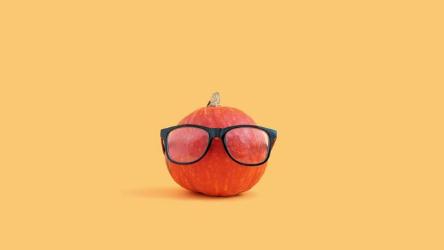 Minimal Halloween concept with pumpkin wearing eyeglasses on orange background 4k.