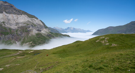 mountain plateau and valley with cloud filling the valley below and clear blue summer sky