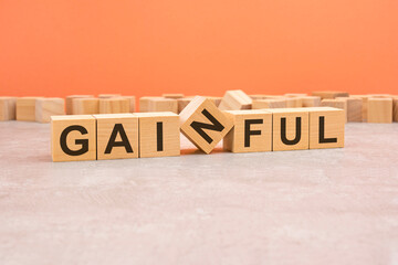 word GAINFUL made with wood blocks. orange background