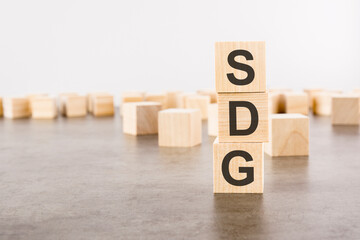 SDG text as a symbol on cube wooden blocks. many wooden blocks in the background.