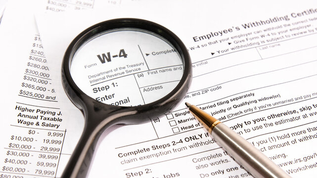 blank form W-4, magnifier and a pen on table. tax season