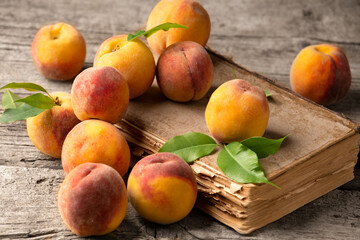 Ripe peaches on book and wooden background